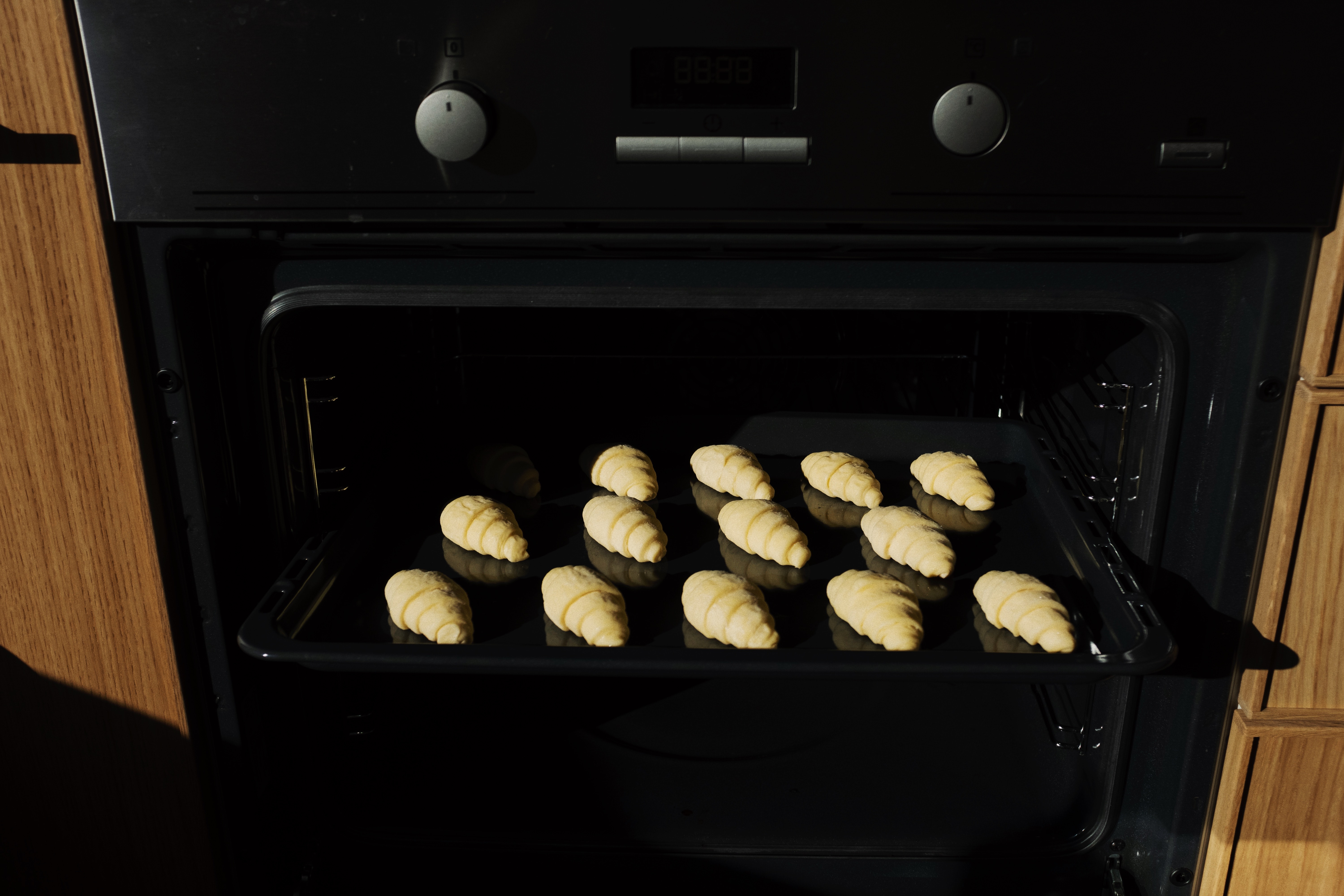 Croissants on a black tray going into the oven